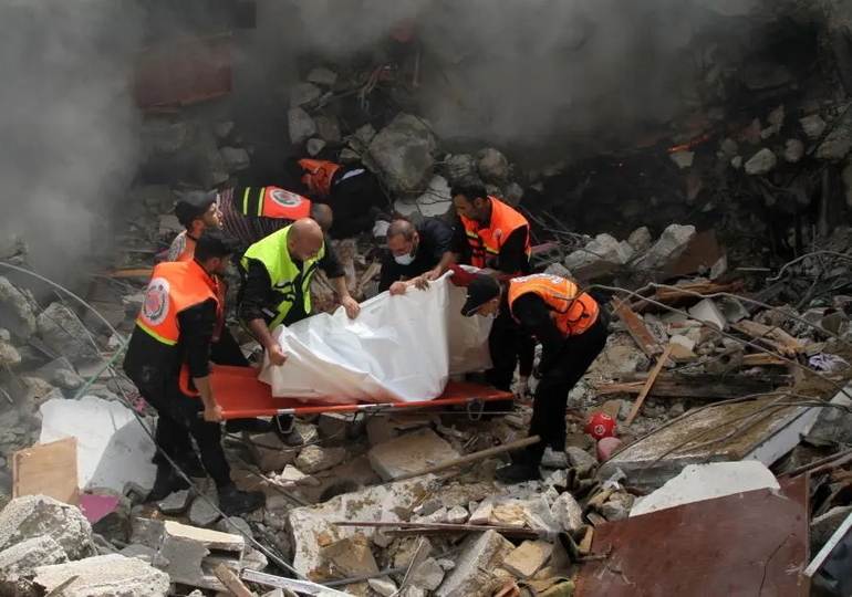 Des membres d’une unité de défense civile palestinienne s’apprêtaient à transporter le corps de l’une des 44 personnes civiles tuées lors de l'effondrement de trois immeubles résidentiels à Gaza, à la suite de frappes aériennes israéliennes menées le 16 mai 2021. © 2021 Rizek Abdeljawad/Xinhua via Getty Images