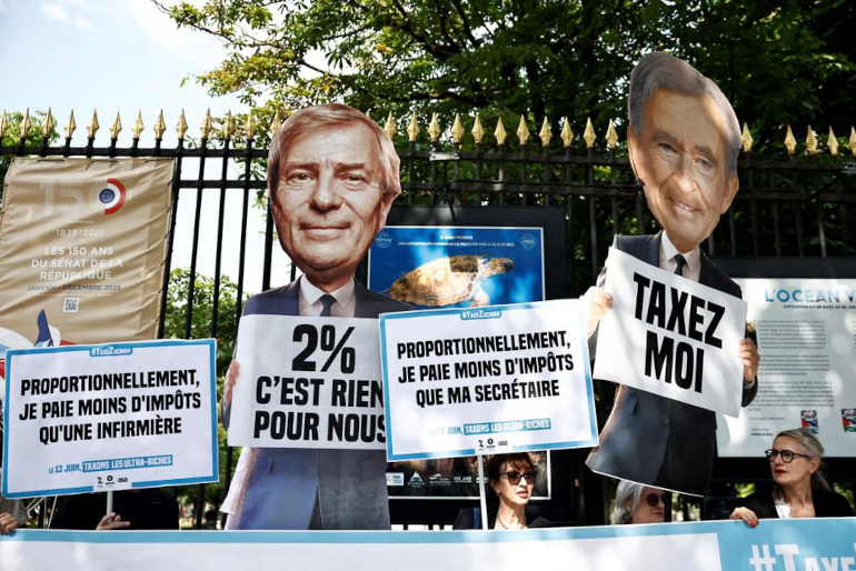 Des militants d’Attac, Oxfam France et 350.org brandissant des pancartes en 2024 sur lesquelles on peut lire « Taxez-moi » et des cartons représentant le milliardaire français Vincent Bolloré et Bernard Arnault, président-directeur général de LVMH Moët...