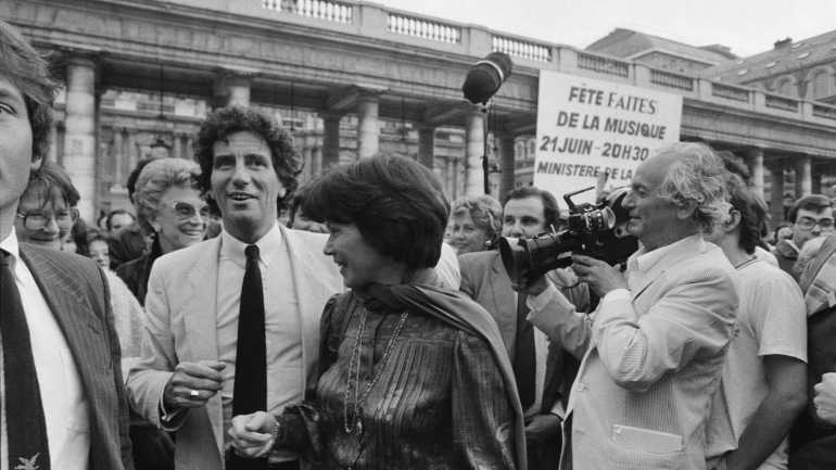 Le ministre français de la Culture Jack Lang (à gauche), la Première dame française Danielle Mitterrand (à droite), le réalisateur français François Reichenbach (à droite) et la productrice française Christine Gouze-Renal (au fond à gauche) assistent à la fête annuelle de la musique au Palais Royal à Paris, le 21 juin 1982.