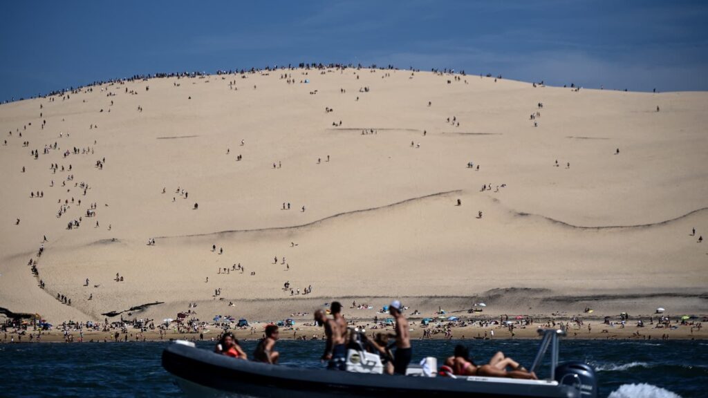 Un bateau passe devant la plage et la dune du Pilat, à La Teste-de-Buch, le 8 août 2023. - Christophe ©ARCHAMBAULT / AFP