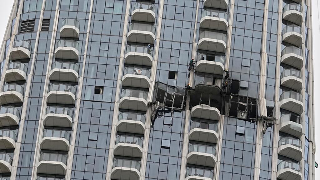 Des ouvriers inspectent les d&eacute;g&acirc;ts caus&eacute;s par une frappe de drone pendant la nuit &agrave; l'h&ocirc;tel Address Creek Harbour &agrave; Duba&iuml;, aux &Eacute;mirats arabes unis, le 12 mars 2026.